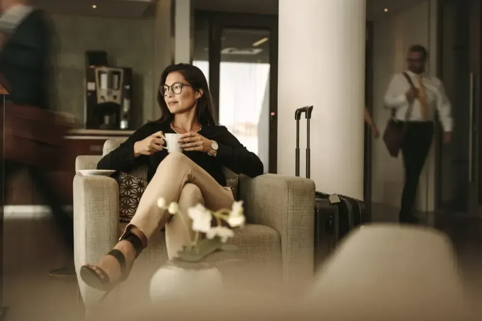 Woman drinking coffee in an airport lounge, looking away from the camera