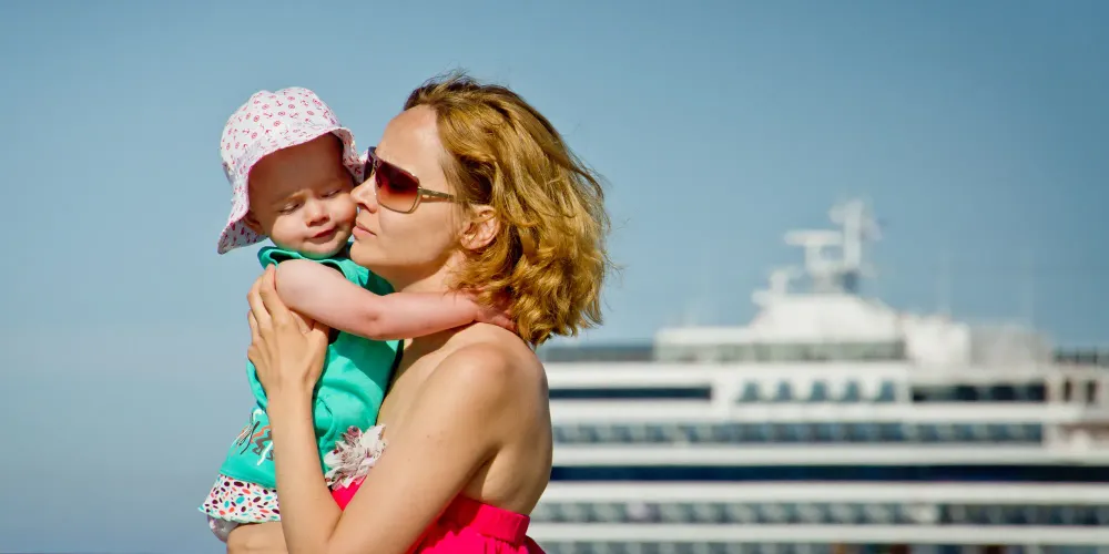 mom holds toddler in front of cruise ship; Courtesy Seleznev Oleg/Shutterstock