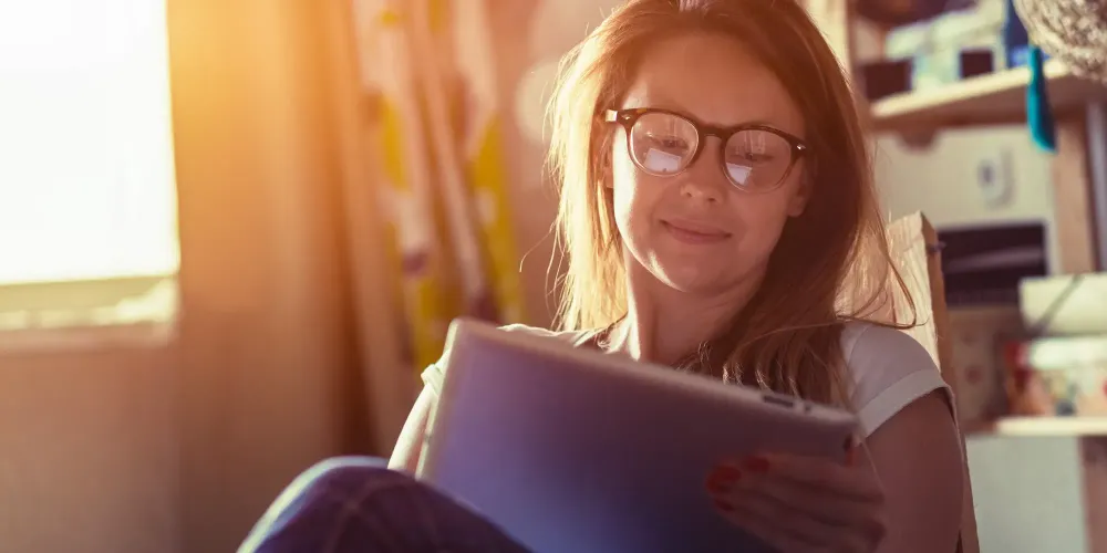 pretty woman with digital tablet sitting in chair at home.
