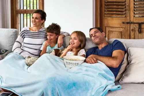 Happy family relaxing on sofa under a blanket; Courtesy Daxiao Productions/Shutterstock