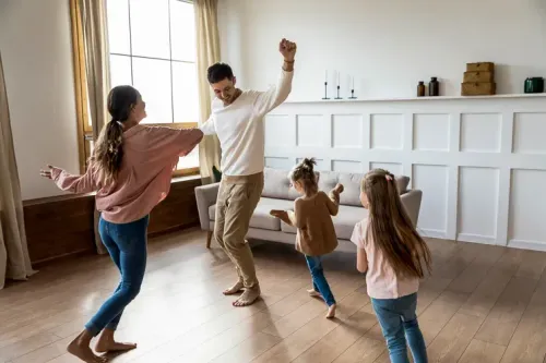 family dancing around living room; Courtesy fizkes/Shutterstock