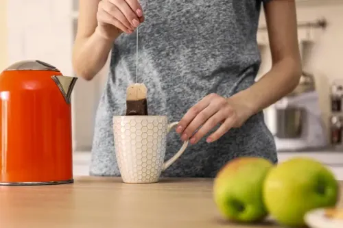 woman making herbal tea in kitchen; Courtesy Africa Studio/Shutterstock