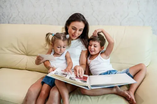 Happy family watching photo album together while sitting on sofa at home