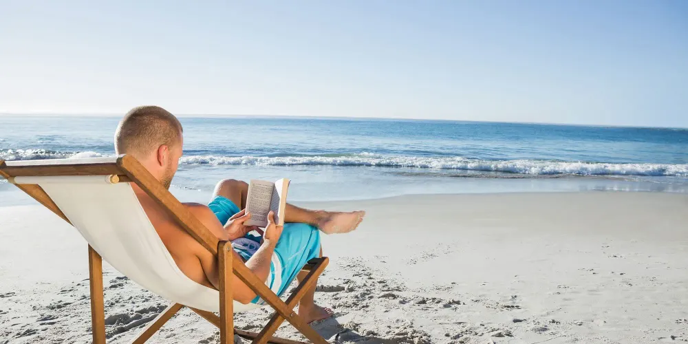 Man Reading a Book on the Beach; Courtesy of wavebreakmedia/Shutterstock.com