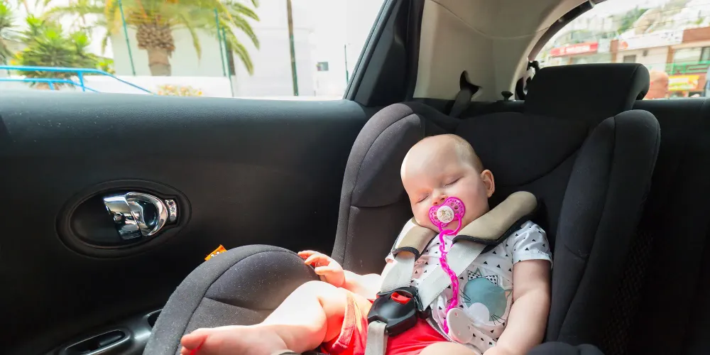 Cute baby girl is sleeping in the car on child safety seat; Courtesy of Patryk Kosmider/Shutterstock