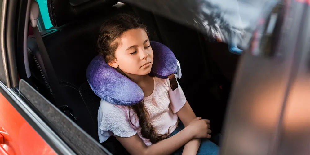 kid sleeping in car with neck pillow; Courtesy of LightField Studios/Shutterstock