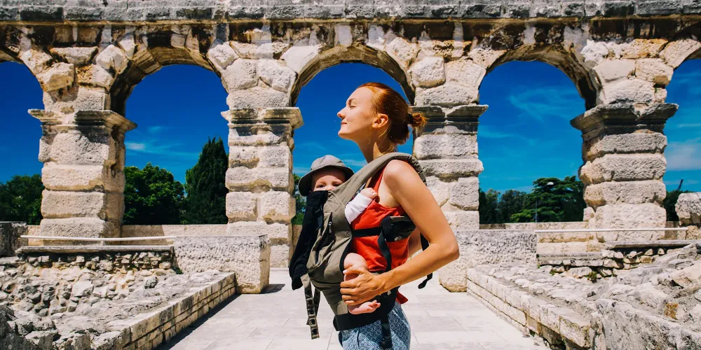 mother with baby child in carrier in the old town of Pula, Croatia; Courtesy of Natalia Deriabina/Shutterstock