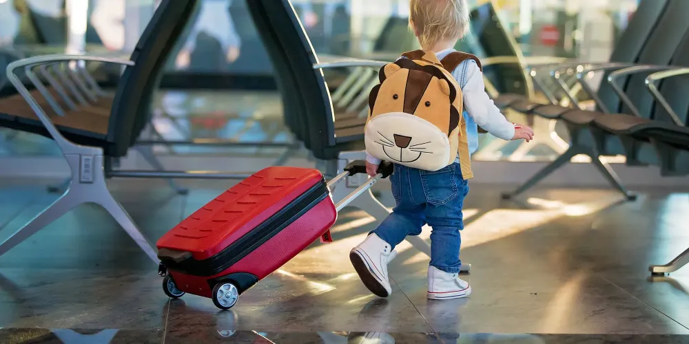 toddler wheeling luggage at airport.; Courtesy of Tomsickova Tatyana/Shutterstock