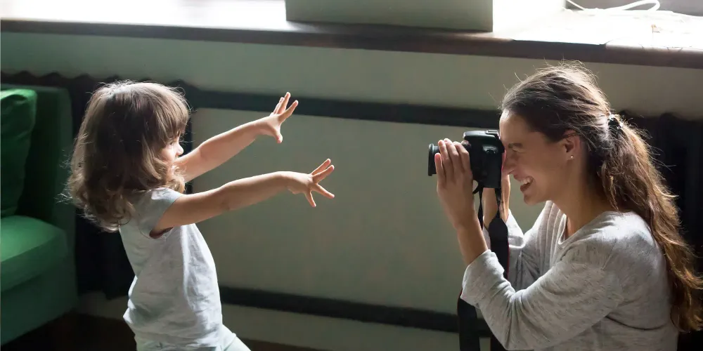 mom taking photo of daughter dslr camera; Courtesy fizkes/Shutterstock