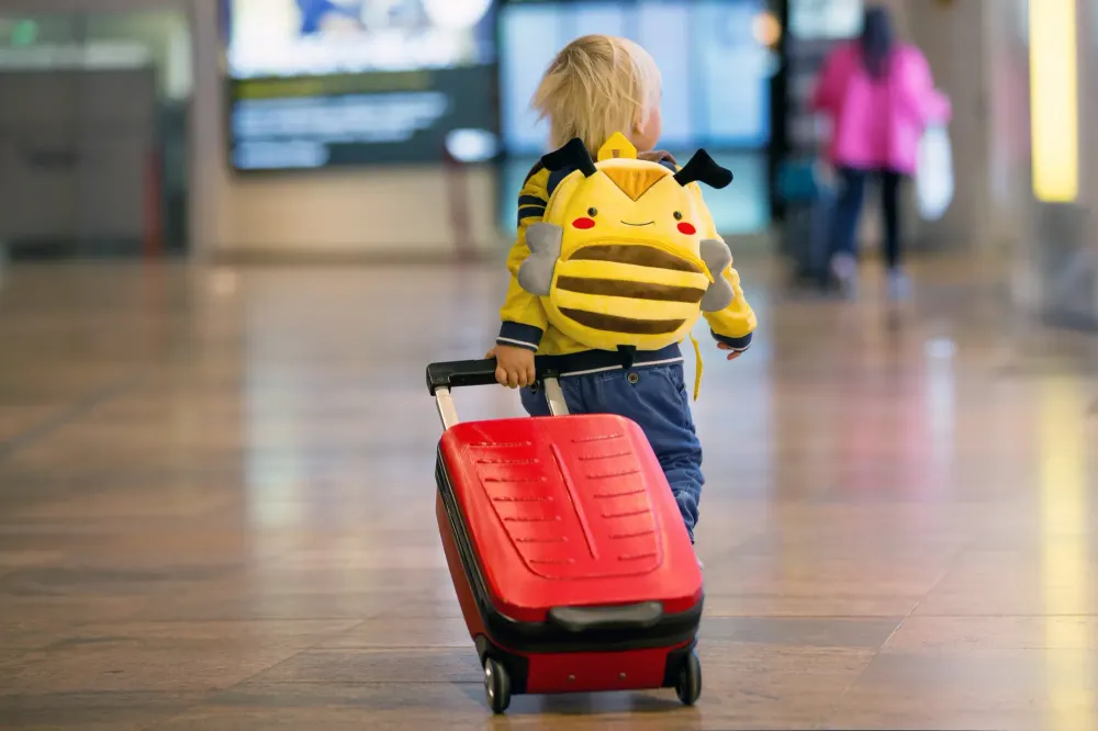 Child walking through airport with suitcase