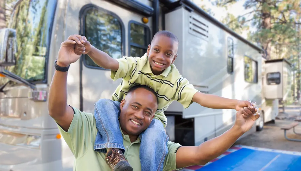 Son on his father's shoulders in front of their RV