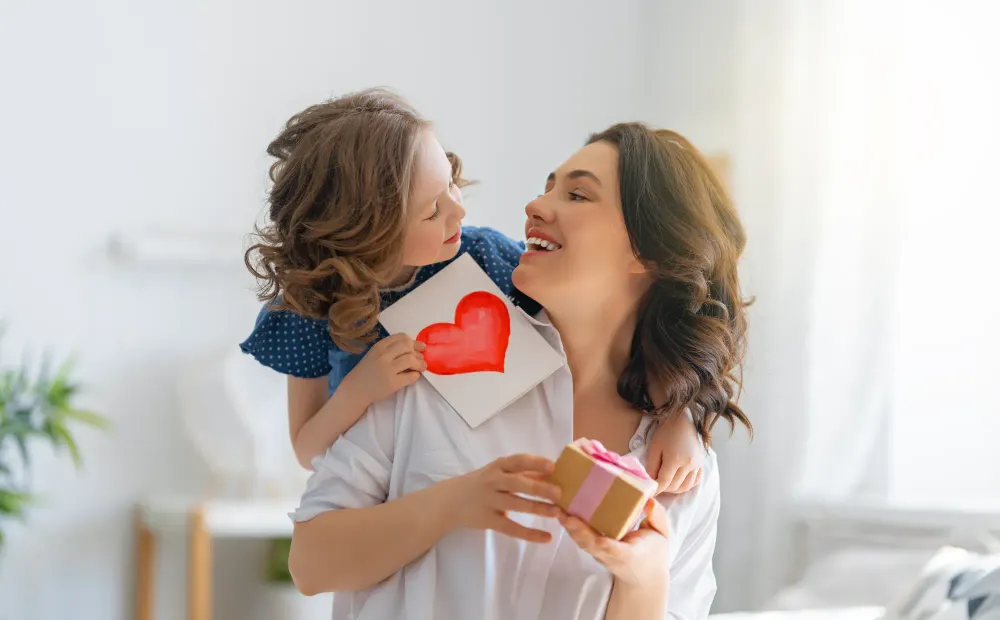 Child giving her mother a card and a gift