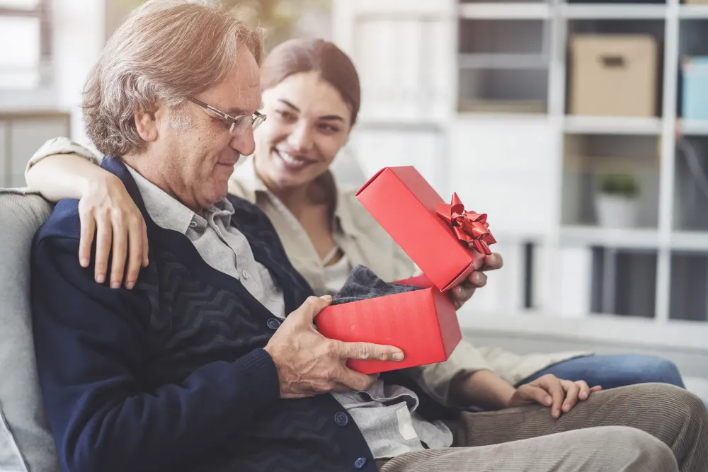Daughter giving father a gift wrapped in a red box with a red bow