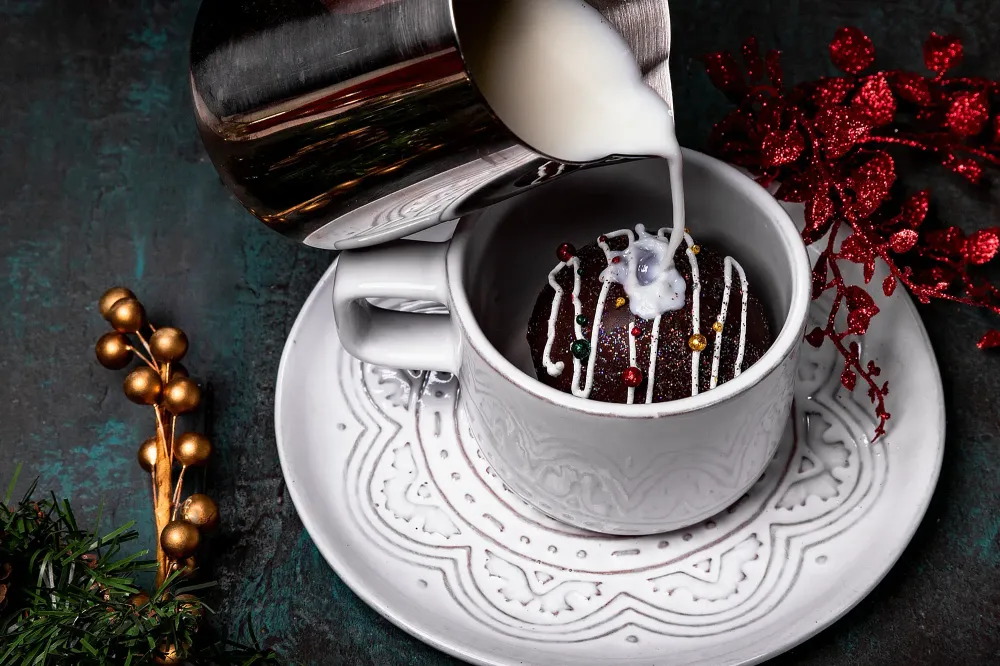Close up of milk pouring over a hot chocolate bomb in a mug