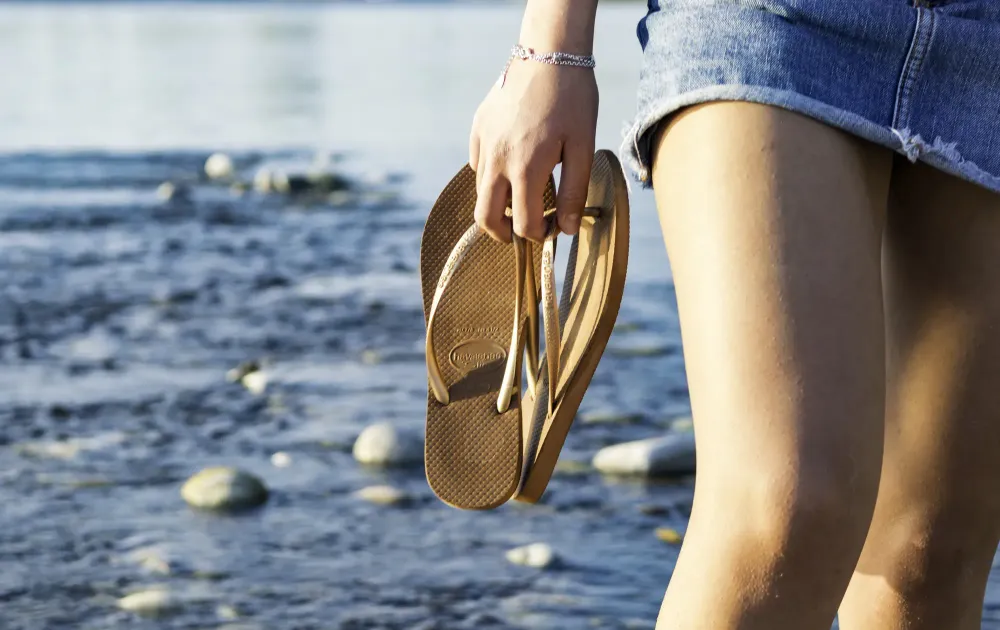 Woman holding flip flops on beach