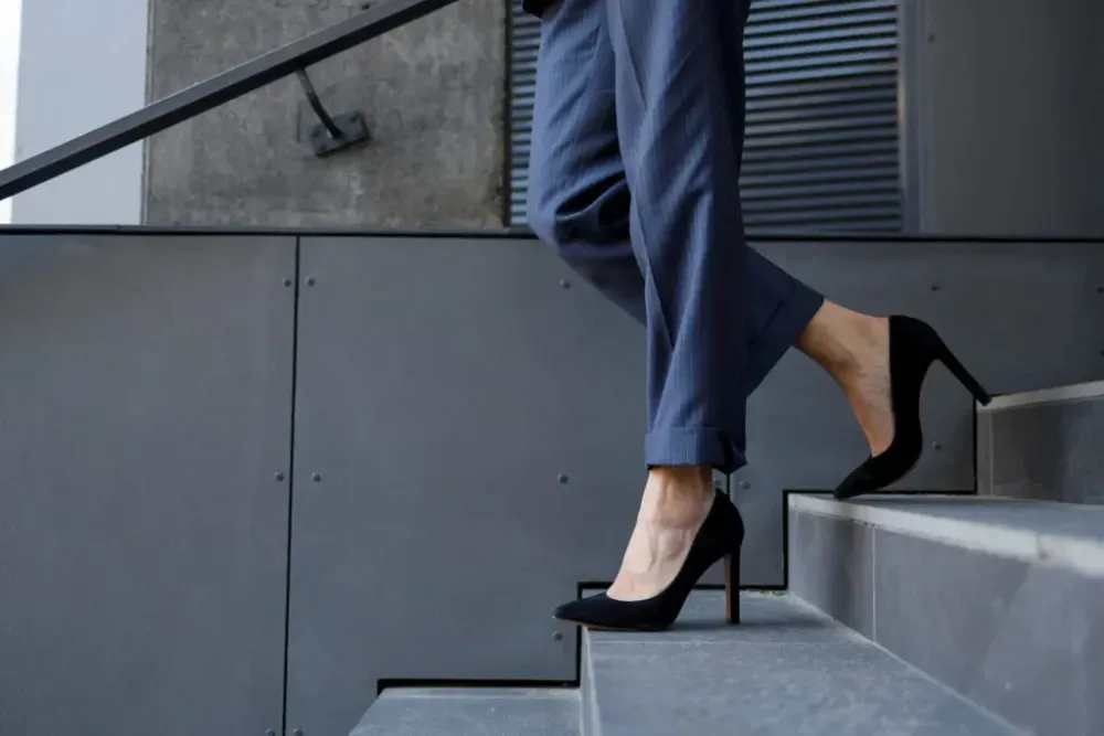 Close up of person wearing black high heels while walking down the stairs