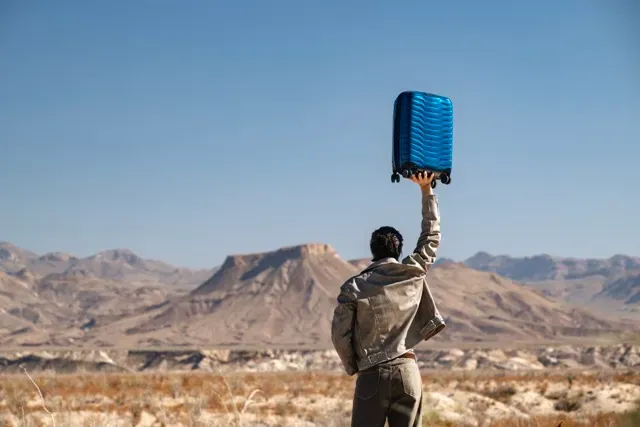 Person holding suitcase over their head