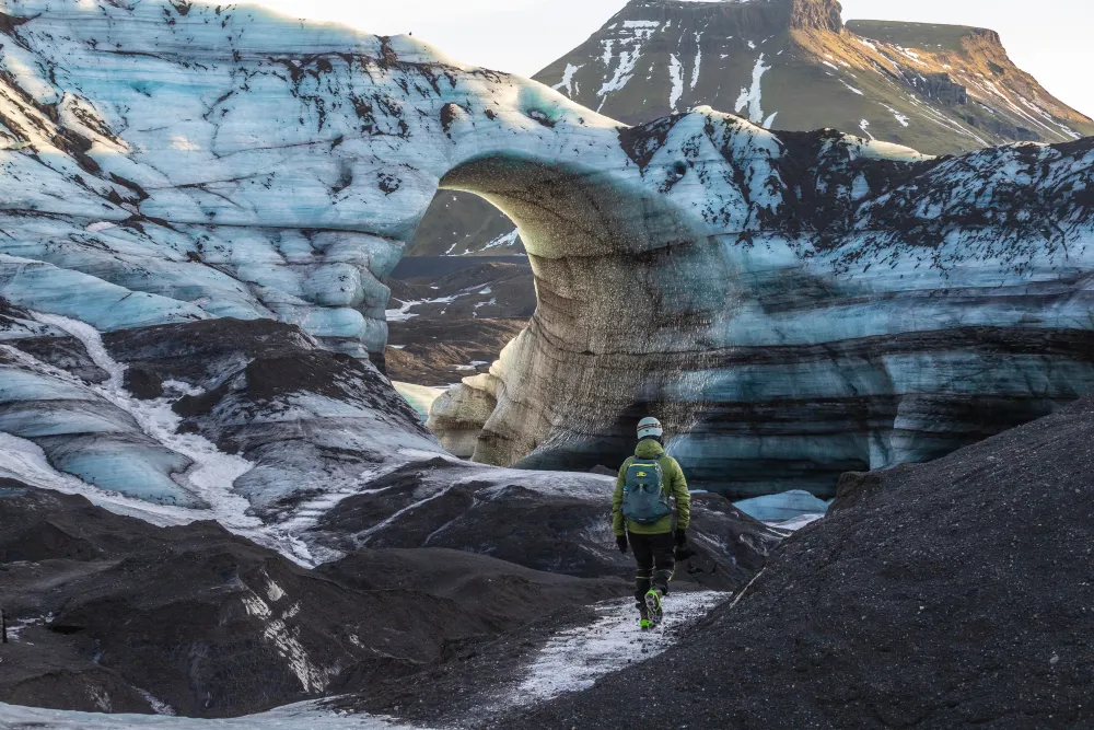 A guy standing in front of the arch of Katla Glacier in Iceland