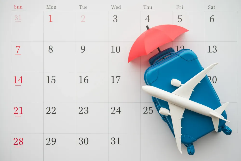 Airplane, suitcase and umbrella on white calendar background.