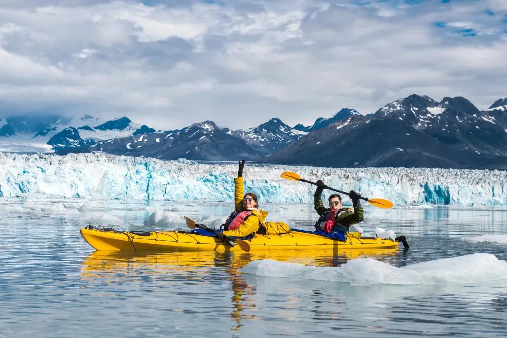 Happy couple enjoys ocean kayaking bear glacier during their vacation trip to in Alaska