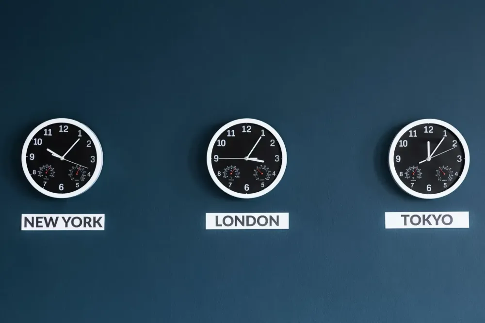 Three clocks on a dark blue wall showing the times in New York, London, and Tokyo